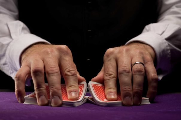 A poker dealer shuffling cards on a table