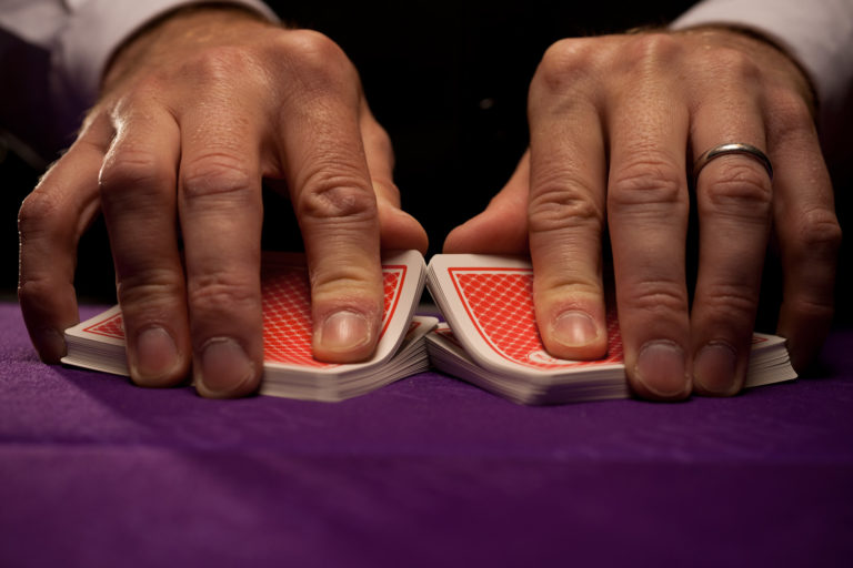 A poker dealer shuffling cards on a table
